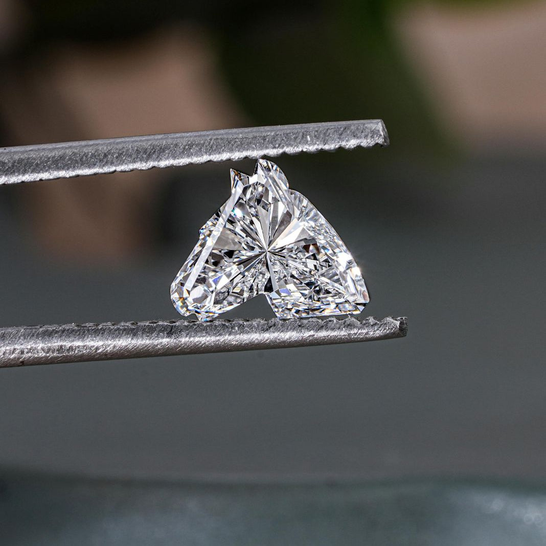 A photo of a heart shaped diamond in a jewellers tweezers
