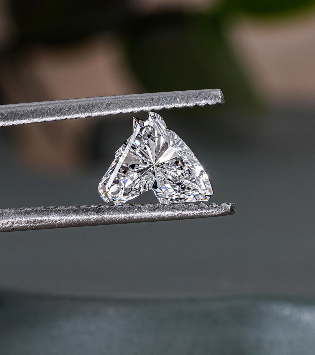 A photo of a heart shaped diamond in a jewellers tweezers