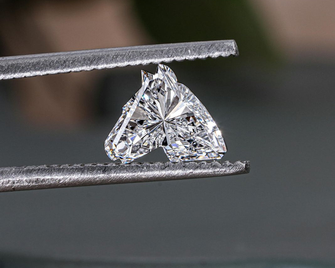 A photo of a heart shaped diamond in a jewellers tweezers
