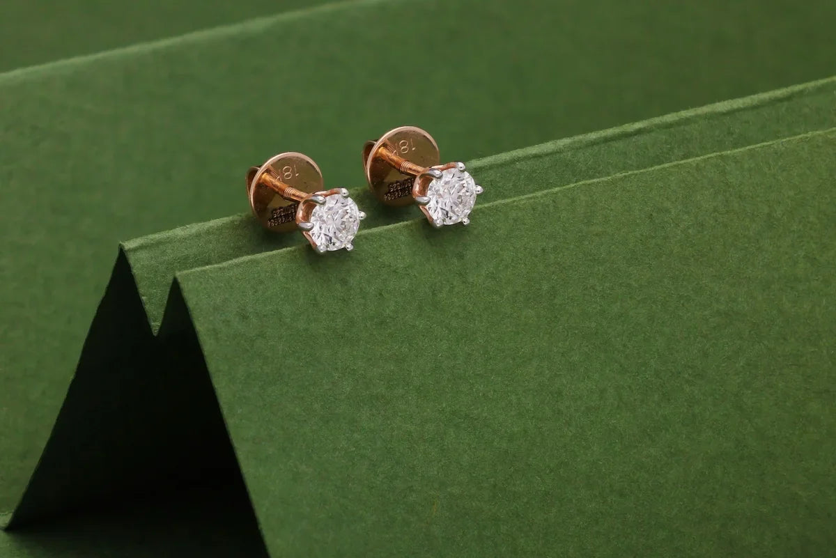  Pair of round diamond solitaire stud earrings in gold settings