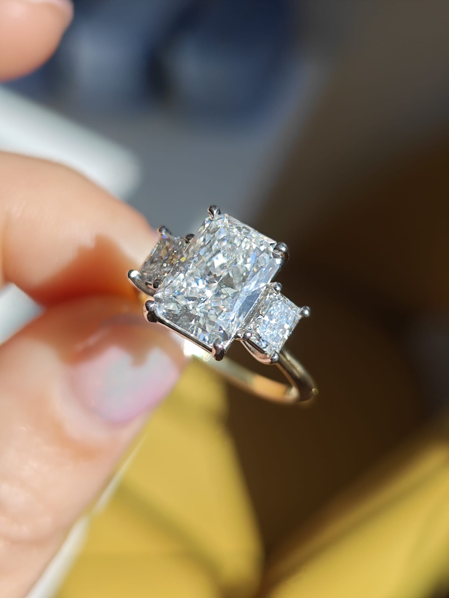 Three-stone engagement ring with a radiant-cut center diamond and two princess-cut side diamonds, set on a sleek white gold band. Timeless elegance and brilliant sparkle for special occasions. - Sample Image