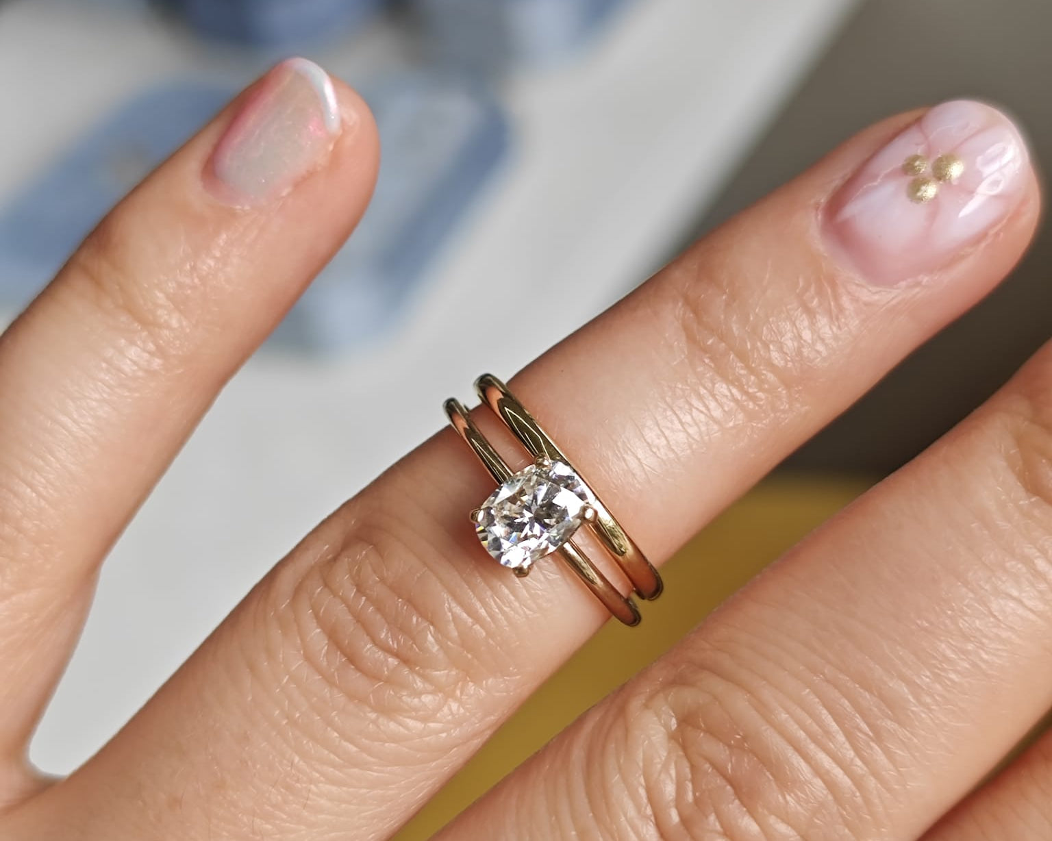 Two-ring set with a central gemstone on a plain band, displayed on a hand. Elegant engagement and wedding ring combination. - Sample Image