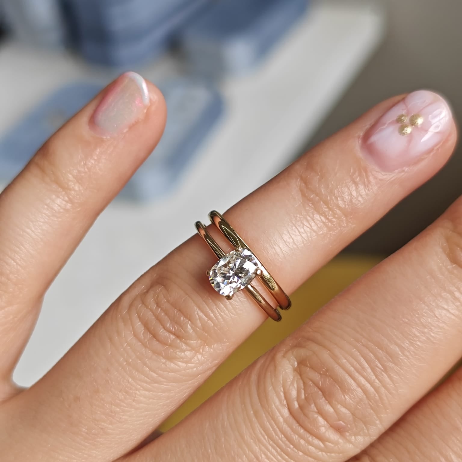 Two-ring set with a central gemstone on a plain band, displayed on a hand. Elegant engagement and wedding ring combination. - Sample Image