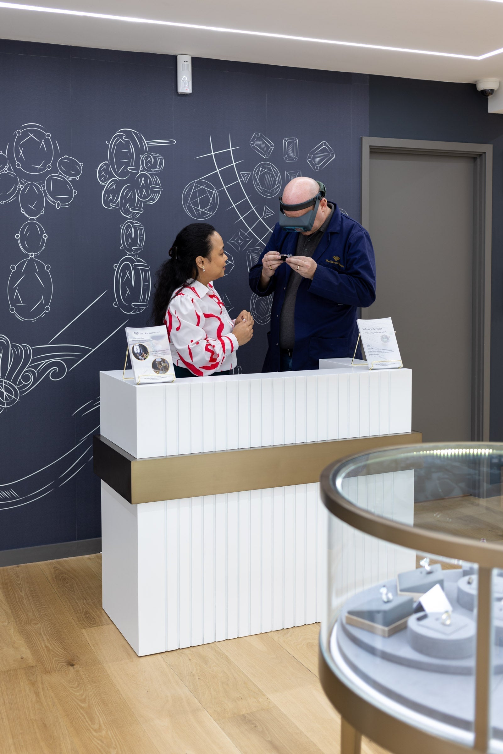 a bespoke engagement ring consultation taking place between a lady and a jeweller who is inspecting a ring