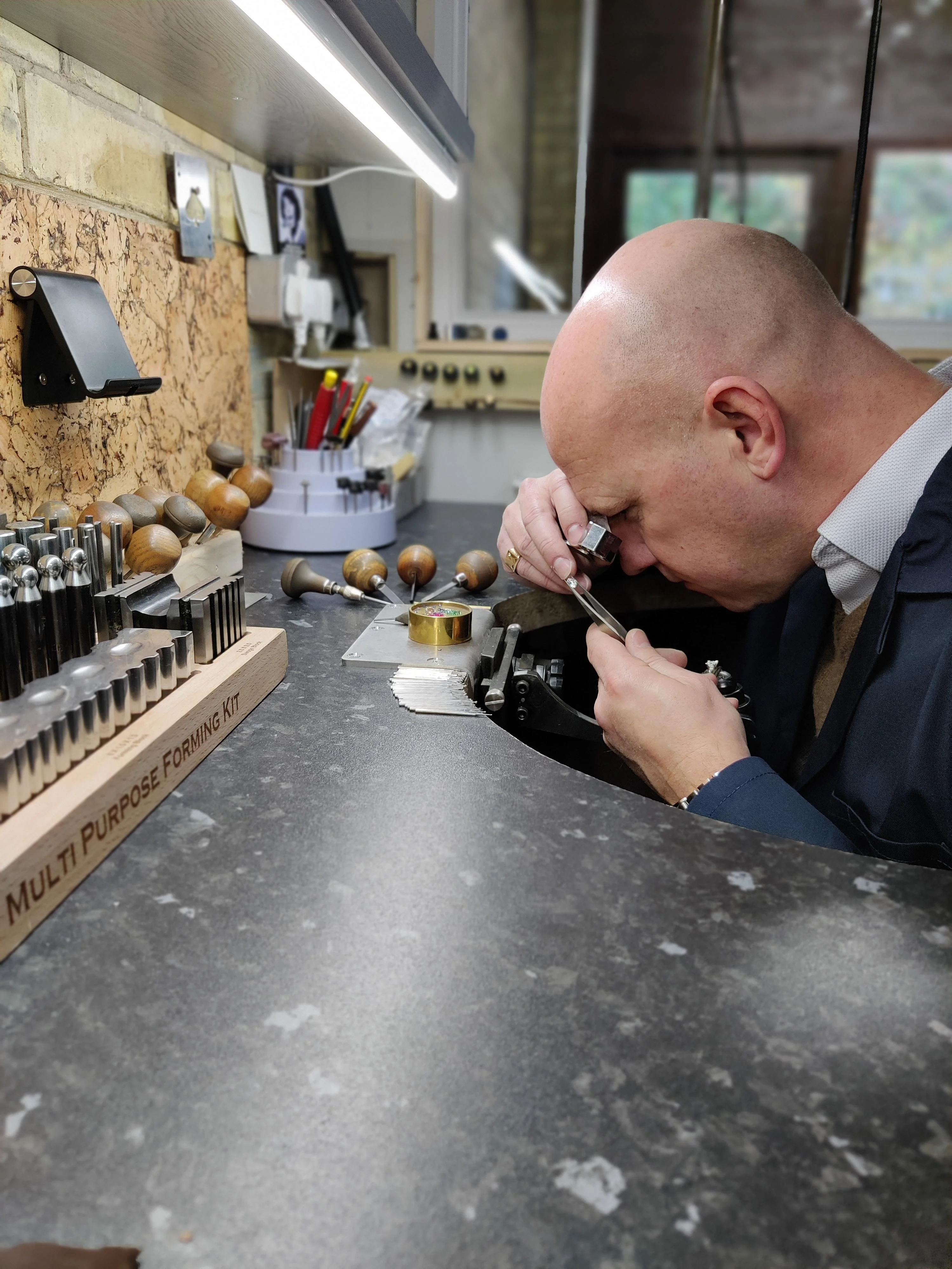 Setting diamonds into an eternity ring at the workshop bench